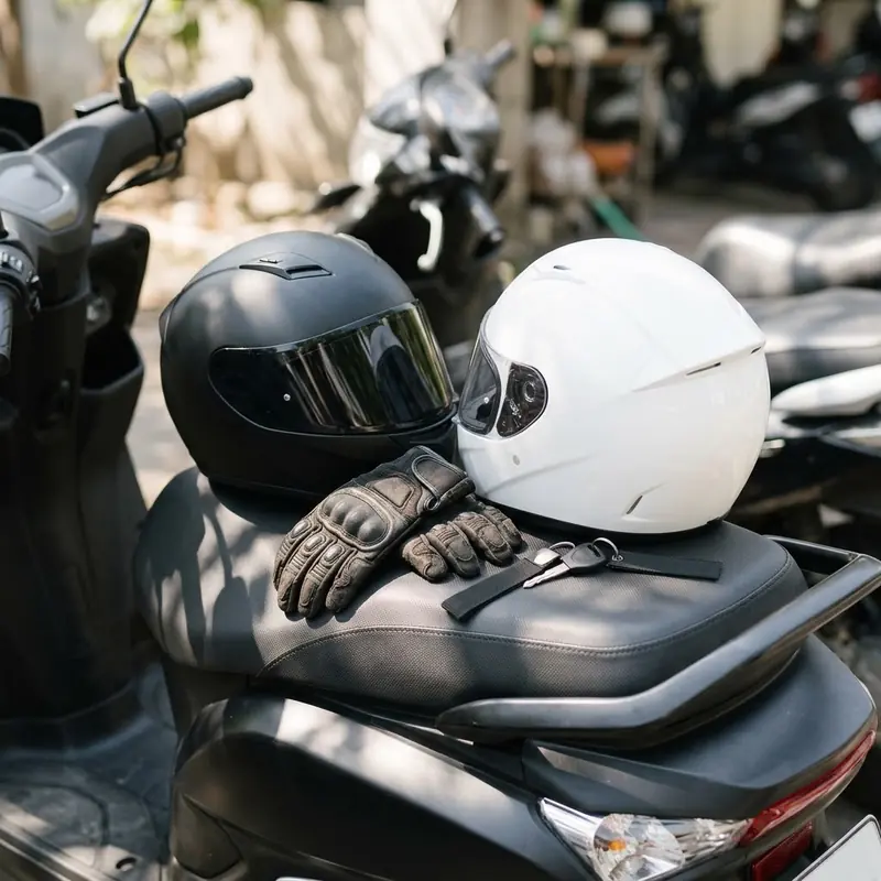 Ilustrasi helm dan sarung tangan di atas jok motor